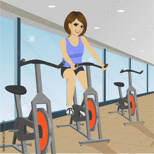 young woman doing indoor biking exercise at gym