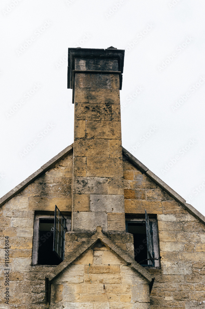 Detail of typical english limestone house in the Cotswolds. Gable and chimney aginst overcast sky