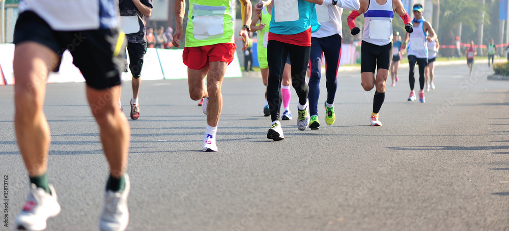 Unidentified marathon athletes legs running on city road Unidentified marathon athletes legs running on city road