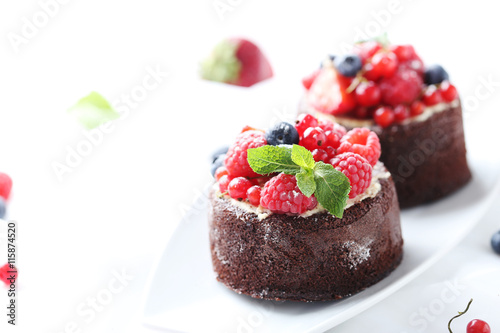 Sweet chocolate cakes with berries on white background