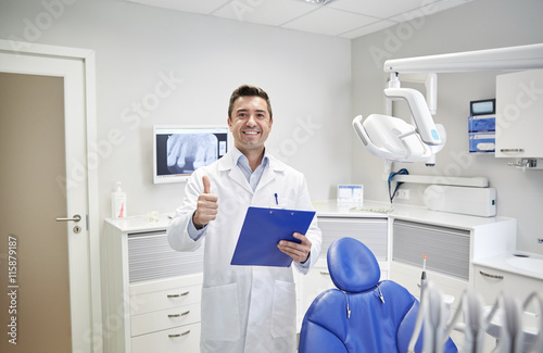 happy male dentist showing thumbs up at clinic