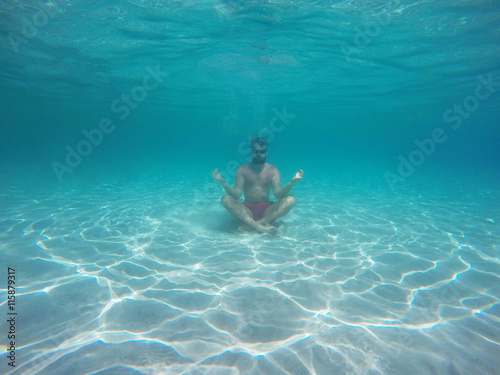 Beard man with glasses in the lotus position meditating under wa