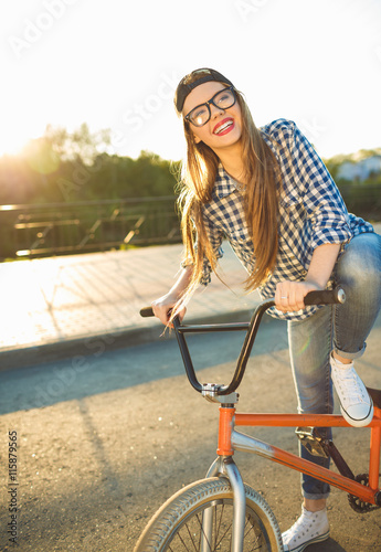 Lovely girl in a hat riding a bicycle in the sunlight outdoor