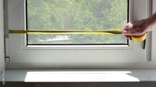 Man measuring a window with yellow centimeter