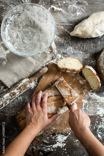 Woman cutting bread on rustic wooden table

