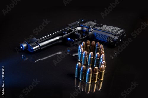 9mm hand gun with rounds on black reflective background