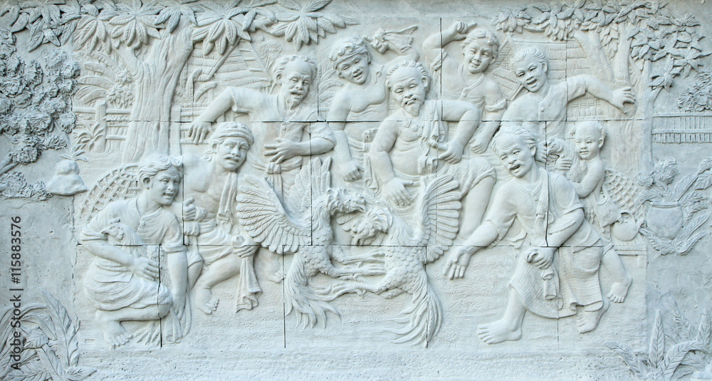 Stone carving of Thai cockfighting sport on temple wall