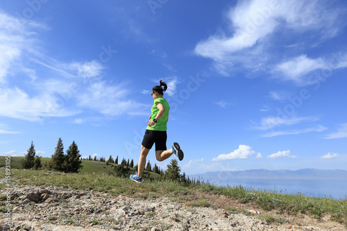 healthy young woman trail runner running on beautiful mountain peak