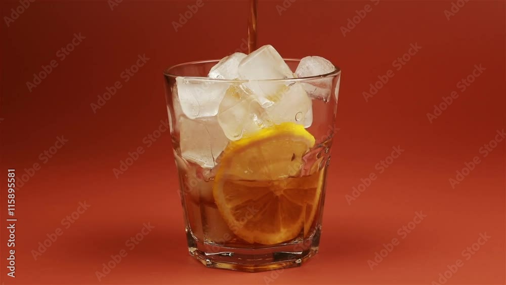 Glass of ice tea with mint and lemon, ice cubes on brown background Glass of ice tea with mint and lemon, ice cubes on brown background