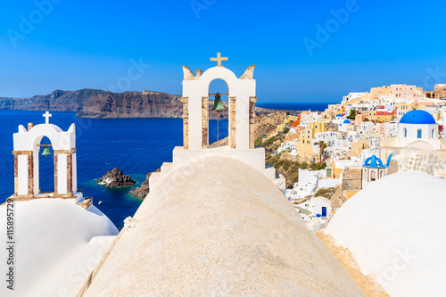 View of famous Oia village with white church buildings in foreground, Santorini island, Greece