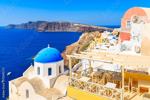 View of famous Oia village with blue dome church and restaurant terrace, Santorini island, Greece