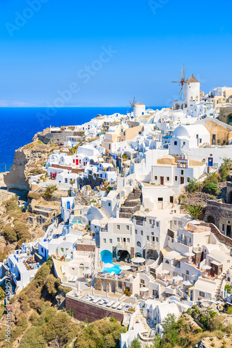 View of famous windmill and white houses in Oia village on Santorini island, Greece