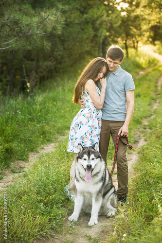 couple in love with a dog, Husky Malamute, sunset forest