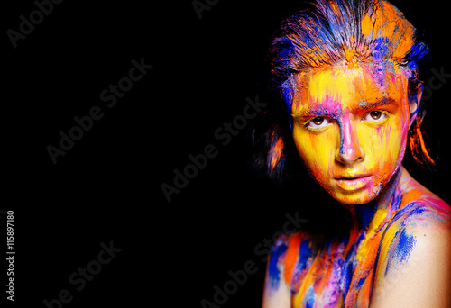 Art makeup. Face, neck and hair girls smeared with bright colors of yellow, blue and pink colors. Holi Festival © irinaneva