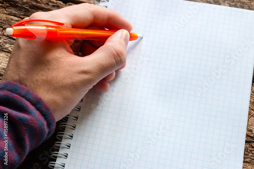 left-handed man writes in a notebook photo