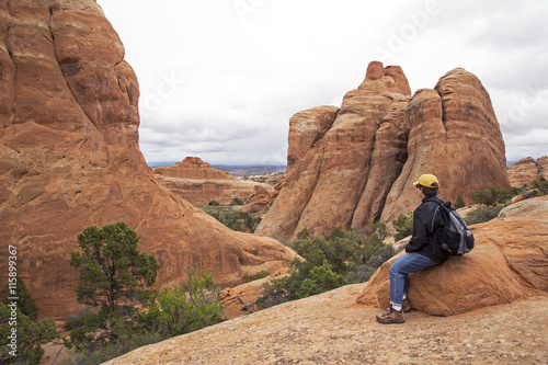 Hiker resting on a trail at Arches National Park Moab Utah.