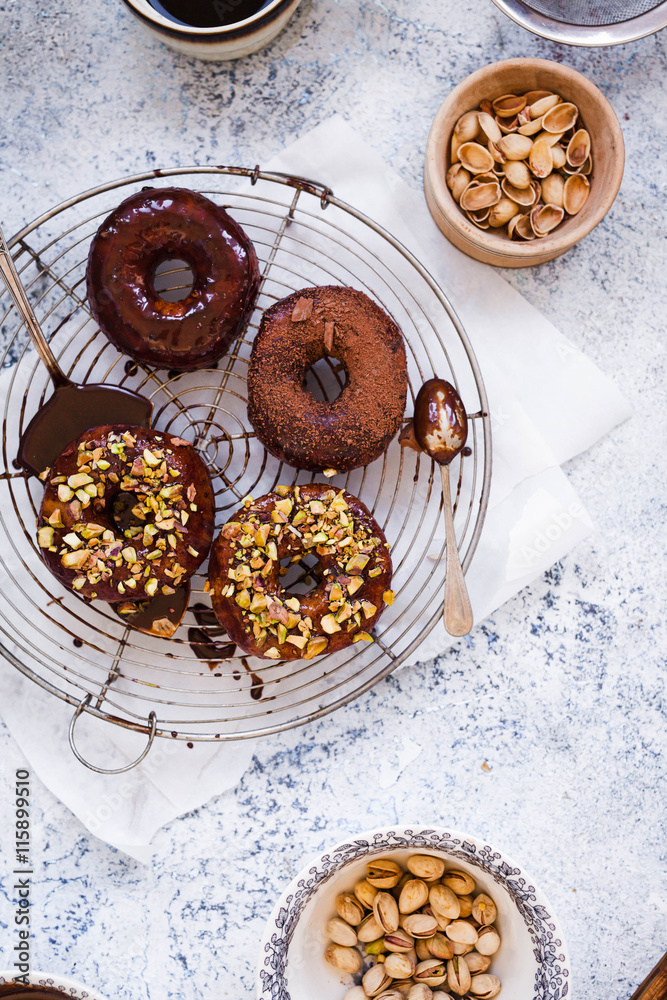 Chocolate donuts over cooling rack with pistachio nuts. Chocolate donuts over cooling rack with pistachio nuts.