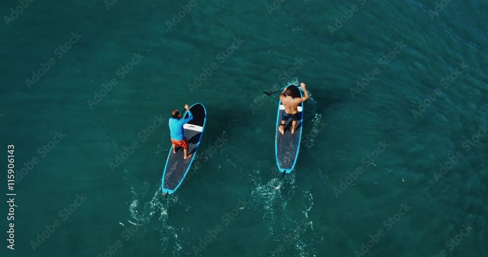 Aerial view of surfer stand up paddle boarding on blue ocean waves