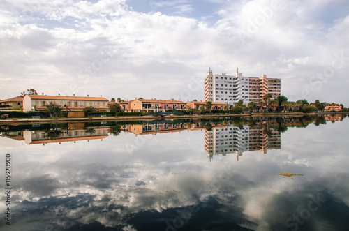 Multi-storey hotel is reflected in the Esperanza lake in Port d'Alcudia. Beautiful reflection of the sky and clouds