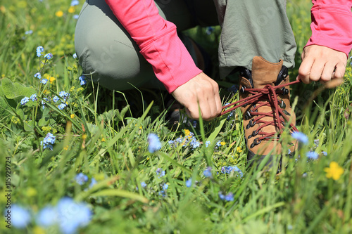 woman hiker tying shoelace on grassland grass
