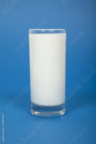 Glas Milch vor blauem Hintergrund