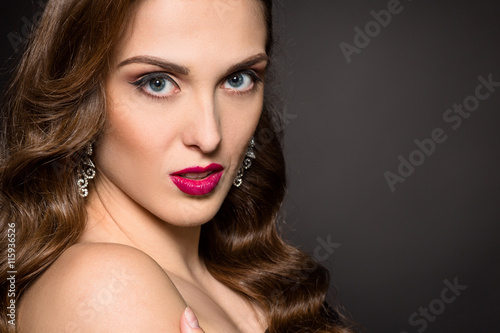 Closeup portrait of beautiful model lady with red lips looking at camera. Young woman posing isolated on black background in studio.