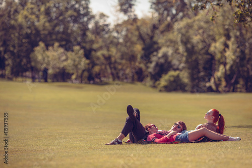 Best friends lying on picnic rug while resting and relaxing in park. People in sunglasses enjoying sunny weather.
