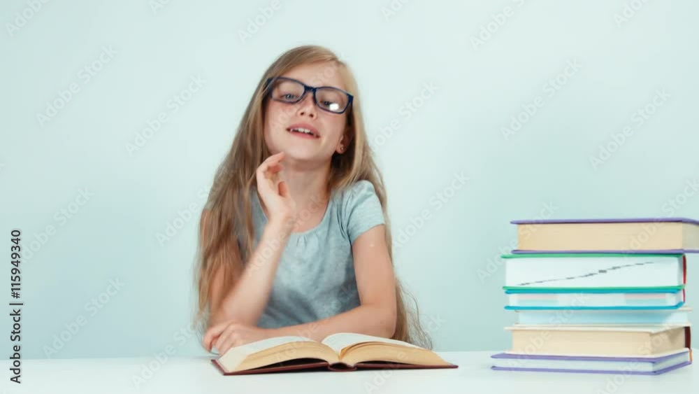 Close up portrait schoolgirl stretching at camera and reading book at the table isolated on white Close up portrait schoolgirl stretching at camera and reading book at the table isolated on white