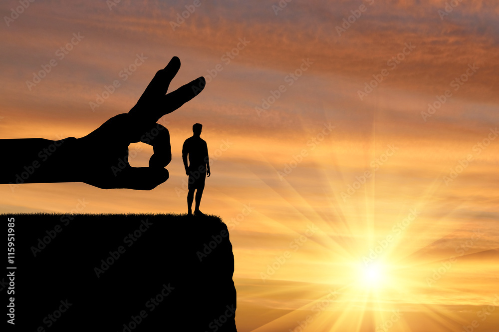 Silhouette hand wants to push a man off a cliff - obrazy, fototapety, plakaty 