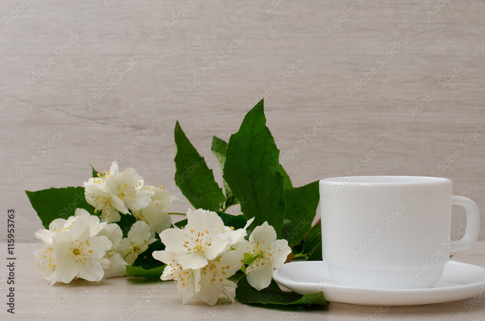 White mug with a sprig of jasmine, close-up White mug with a sprig of jasmine, close-up