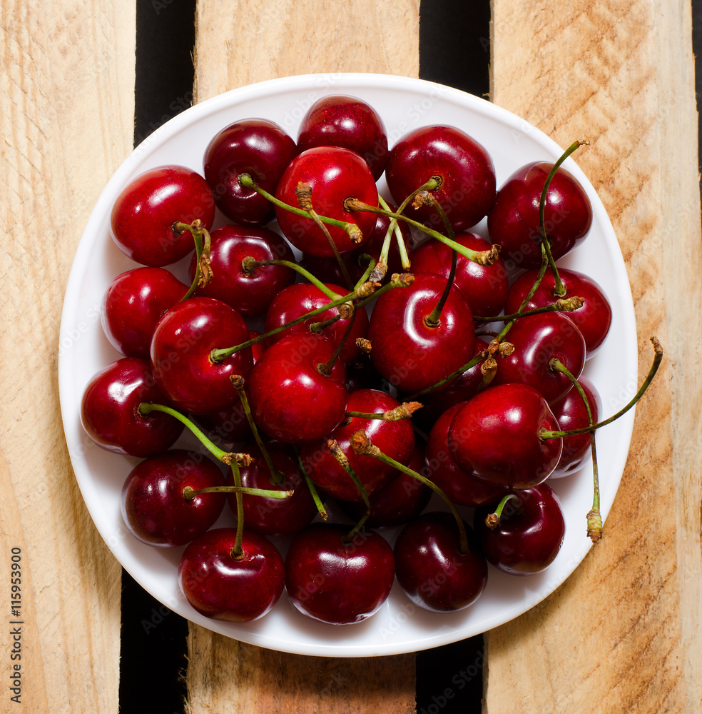 Red cherry in a plate on wooden boards, top view Red cherry in a plate on wooden boards, top view