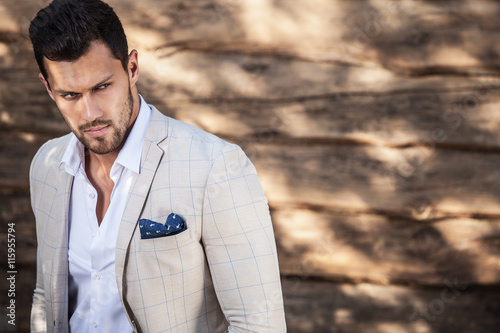 Portrait of young beautiful fashionable man against wooden wall. photo