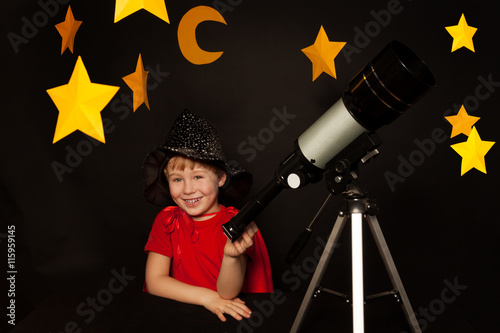 Happy boy with a telescope on black background photo