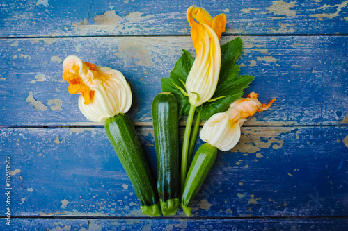 Vászonkép Flowering and ripe zucchini on blue wooden background