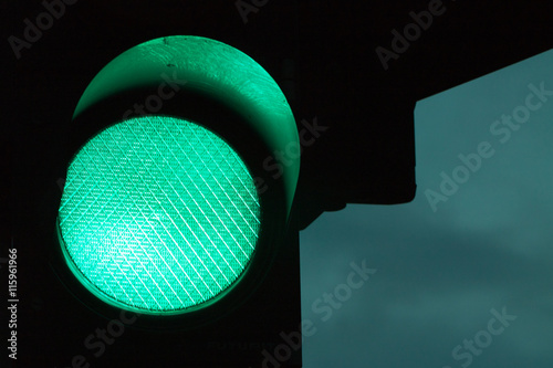 Green traffic light by night and dark sky at the background