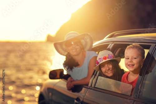 Mother with two kids travel by car on summer vacation, sunset
