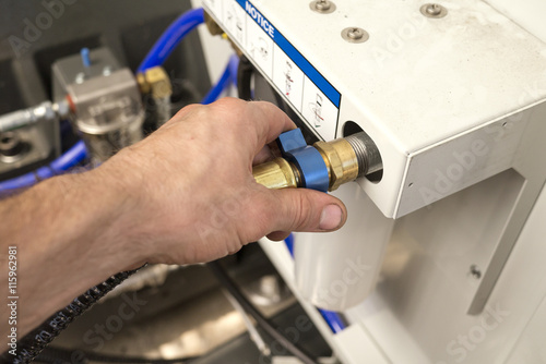 Εκτύπωση καμβά Hand of a man is tightening union nut of the hydraulic pipe