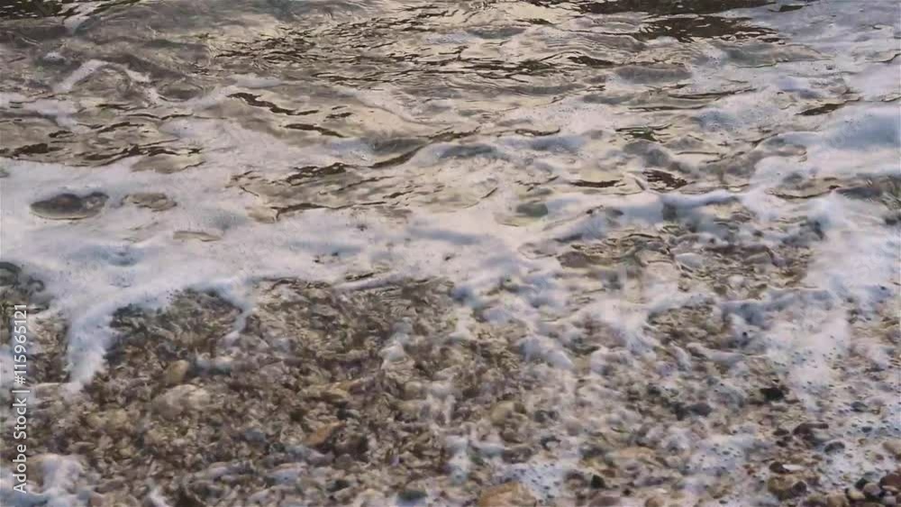 Sea surf at the coast, water with white foam splashing to the pebble beach, natural summer vacation relaxing concept Sea surf at the coast, water with white foam splashing to the pebble beach, natural summer vacation relaxing concept