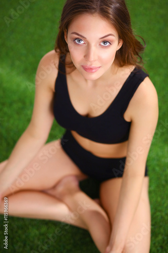 Woman sitting with crossed legs on the green grass