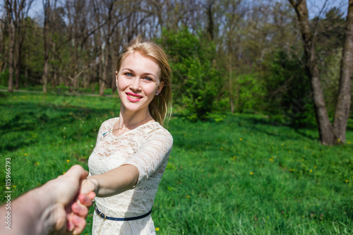 Fototapeta Naklejka Na Ścianę i Meble -  Lovely happy blonde holding my hand and dancing around in blossom garden. Point of view