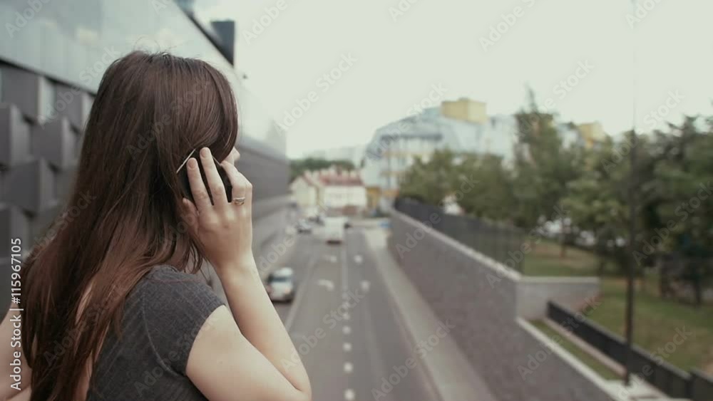 sexy business woman using smartphone standing on a bridge overlooking the road, steadicam shot. slow mo sexy business woman using smartphone standing on a bridge overlooking the road, steadicam shot. slow mo