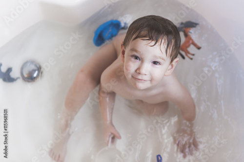 Young Boy Taking a Bath 2 / A young boy in a bath tub smiling and looking up.