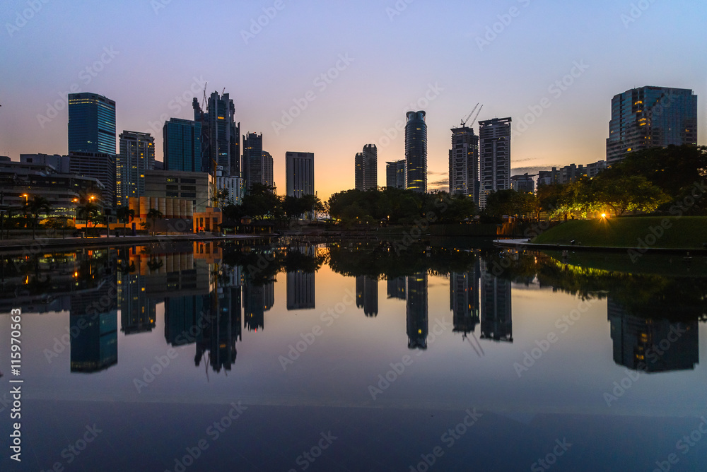 Tranquil blue hour pre dawn scene of Kuala Lumpur skyline reflected in calm lake water 