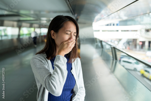 Woman suffer from nose allergy inside pedestrian bridge