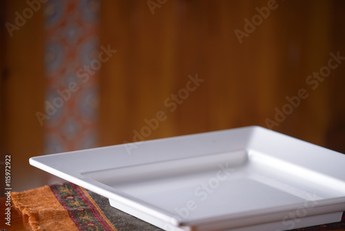 Empty white plate on wooden table over wood background