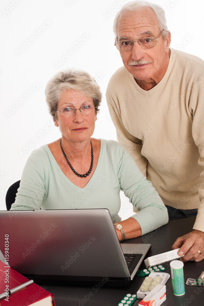 couple de séniors devant un ordinateur avec des médicaments