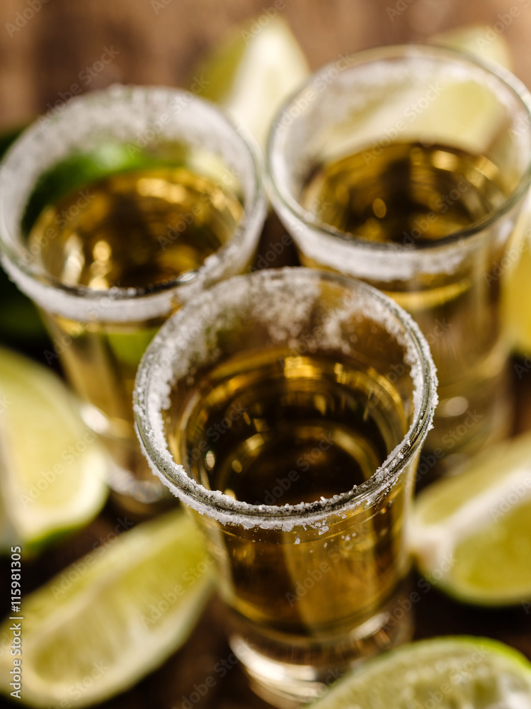 Mexican Gold Tequila with lime and salt on wooden table, selective focus. Top view. Shallow depth of field. Mexican Gold Tequila with lime and salt on wooden table, selective focus. Top view. Shallow depth of field.
