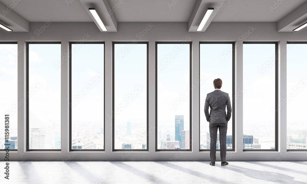 Fototapeta premium Businessman in office room with big panoramic windows