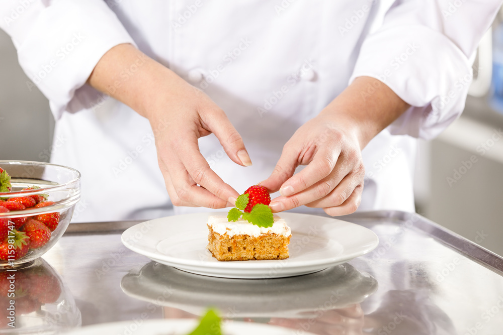 Close-up of chef decorating dessert cake with strawberry Close-up of chef decorating dessert cake with strawberry
