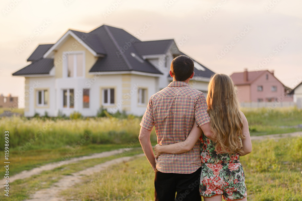 Obraz premium widok z tyłu młodej pary patrząc na ich nowy dom